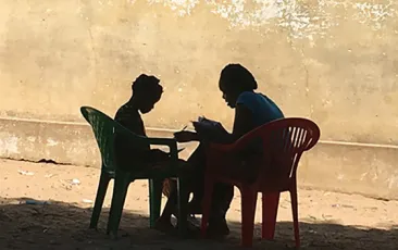 Adult and child reading in silhouette in Mozambique