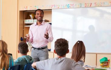 Black educator teaching at front of classroom