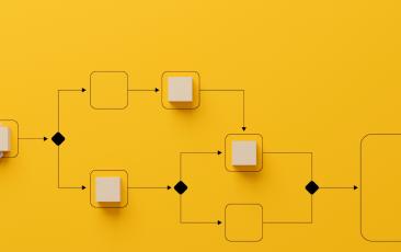 logic model on yellow background with a hand holding cubes that form a flow diagram with lines, blocks and diamond shapes.