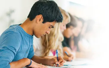 Teenagers sitting in a row doing schoolwork