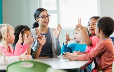 female teacher clapping hands and counting with elementary students