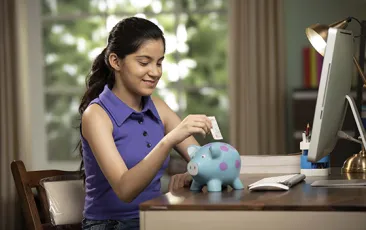 girl putting money in piggybank