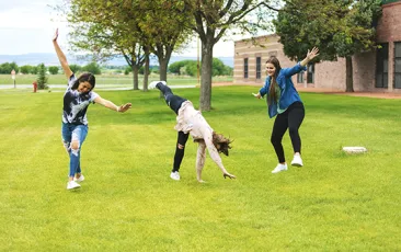 Teenage girls cartwheeling outside Colorado school