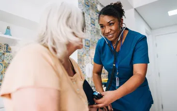 nurse taking blood pressure of elderly patient