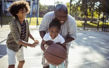 Older man playing basketball with grandchildren
