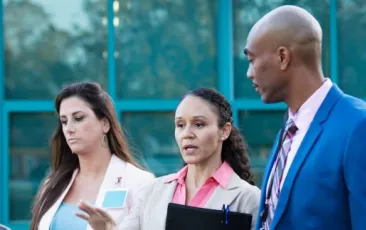 three principals talking outside a school