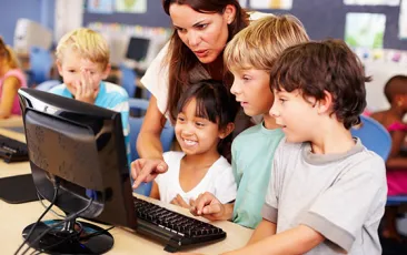 teacher working with students on a computer