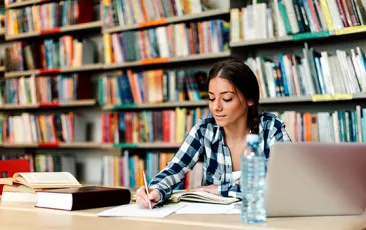 high school student doing schoolwork in library