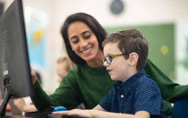 teacher and elementary student working on a computer