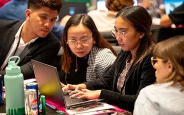 participants in Season of CS event looking at laptop together