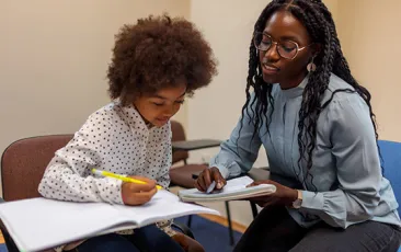 Teacher and student working together at desk