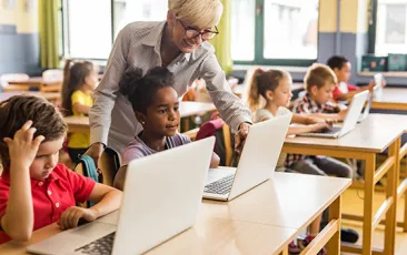 Teacher with young students on laptops