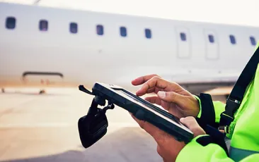 Airport employee with iPad in front of airplane