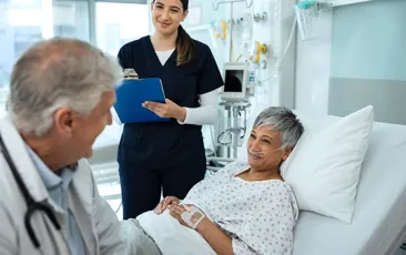 Provider and older patient in hospital bed