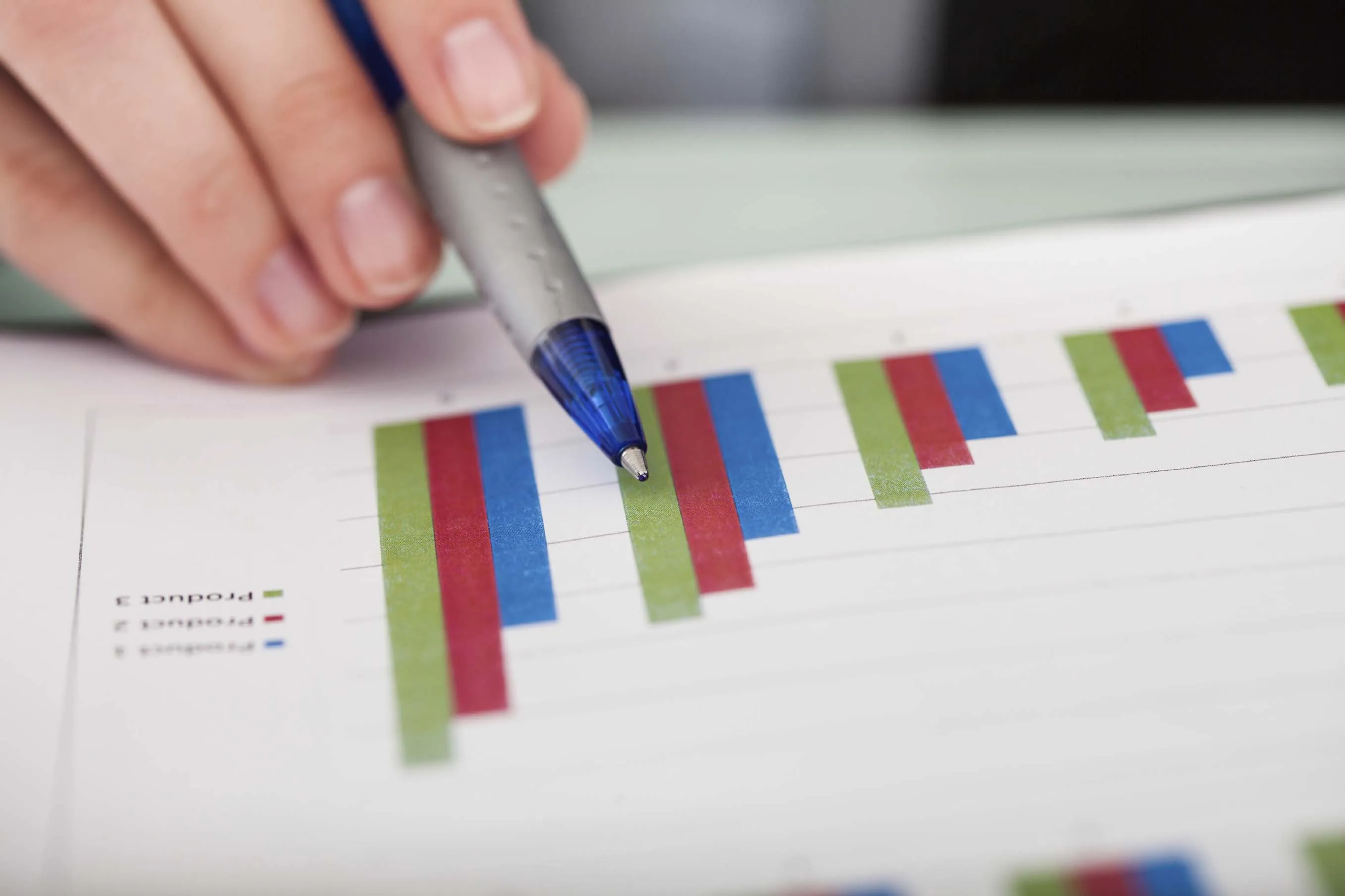 Pen and hand pointing at graphs on page