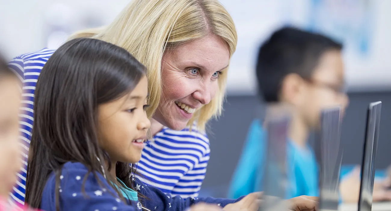 Teacher and student working on laptop