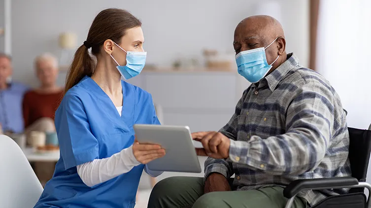 Older male patient with doctor, both wearing masks