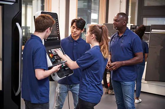 Engineer showing apprentices how to use machine
