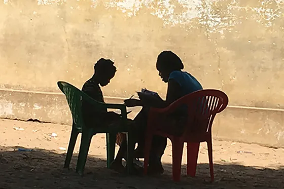 Adult and child reading in silhouette in Mozambique
