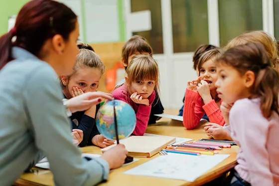 Social studies teacher with a globe and young students