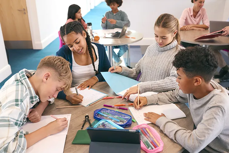 Group of teenagers working on schoolwork at a table
