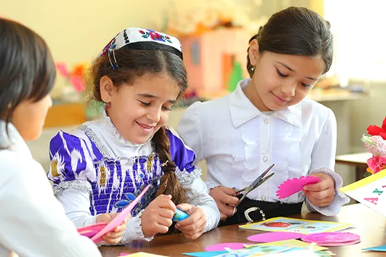 Students cutting paper in classroom