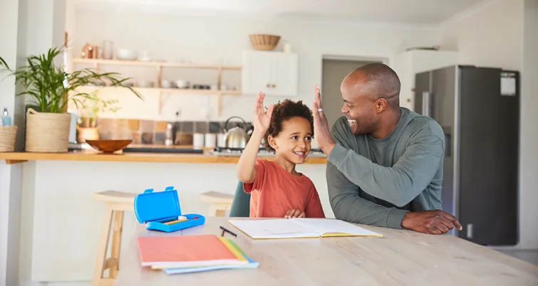 Dad and son high fiving over homework at kitchen island