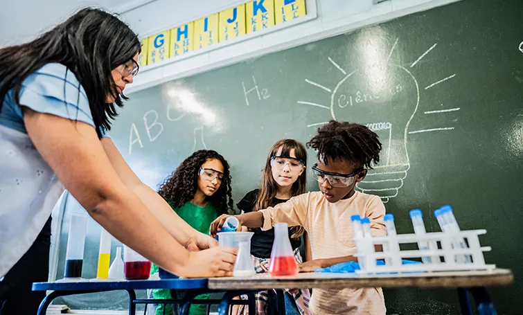 Elementary students working on science experiment with teacher