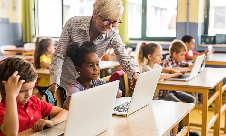 Teacher with young students on laptops