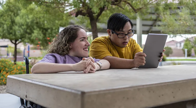 Friends with disabilities looking at an iPad together