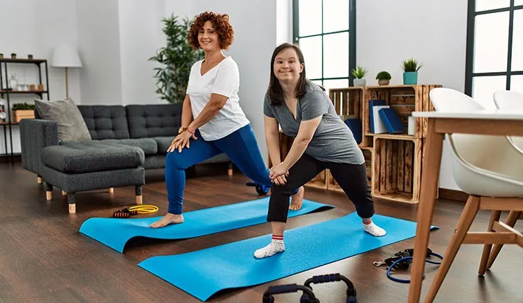 Young woman with Down syndrome and her mother doing yoga