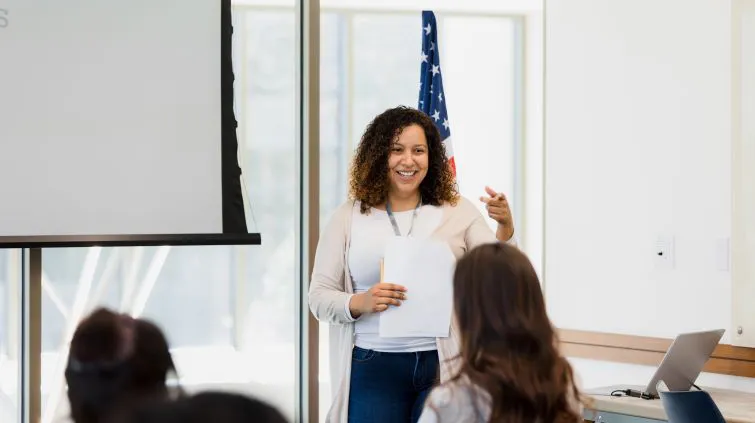 Teacher answering questions in front of a classroom
