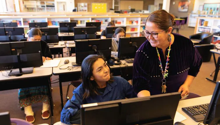 Teacher helping student in computer lab