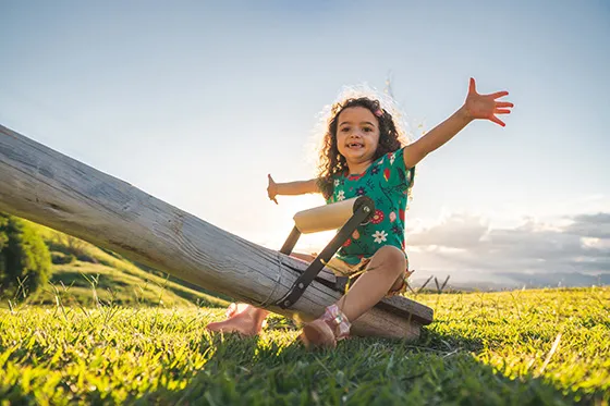 Girl on seesaw with arms spread wide