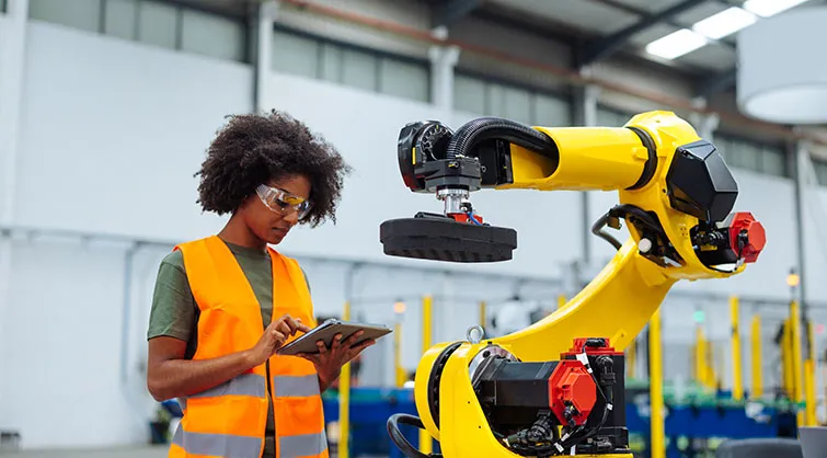 Woman working with robotic arm in factory