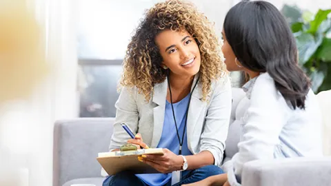 Woman with clipboard talking to colleague