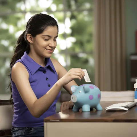 girl putting money in piggybank