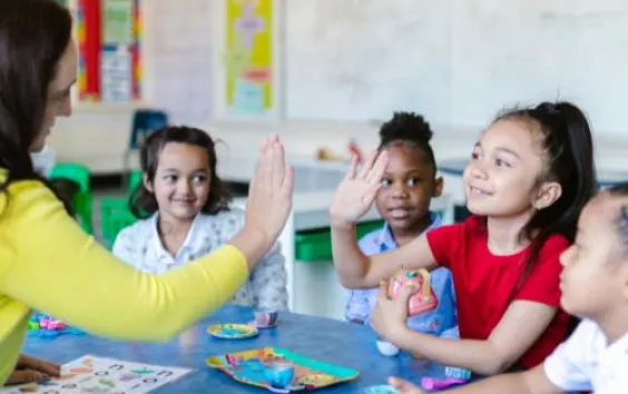 a teacher with four elementary students giving high-fives