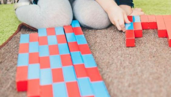 young girl using red and blue blocks to measure 