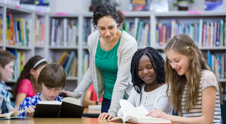teacher in library working with students