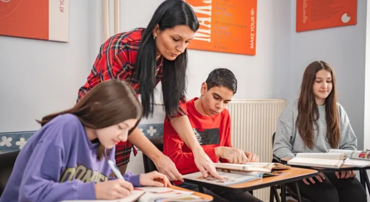 Teacher helping student at desk.