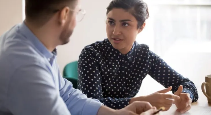 Two teachers talking at table.