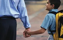 Image of boy with backpack holding his father's hand