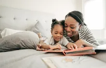Image of mother with young girl reading on bed together