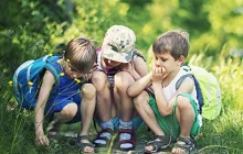 Image of young children looking at bugs in a field