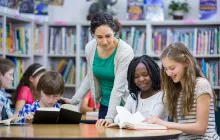 teacher in library working with students