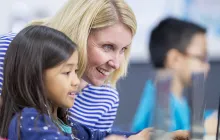 Teacher and student working on laptop