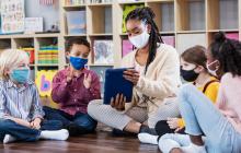 Teacher with iPad and young kids with masks