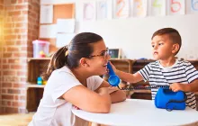 Teacher and young student playing with toy phone
