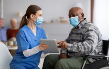 Older male patient with doctor, both wearing masks
